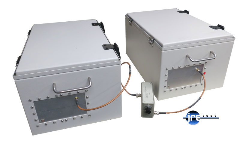 Two JRE 1812 test enclosures connected by coaxial cable through an external step attenuator, both lids closed so every signal between them passes through the attenuator
